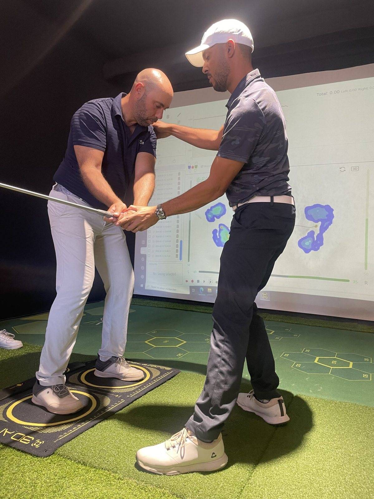 Enseignant de golf corrigeant la position des appuis d'un joueur en salle