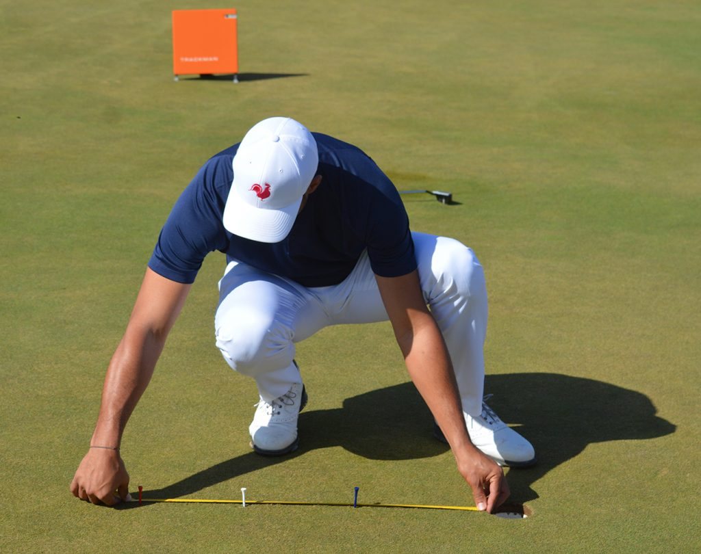 Golfeur posant des repères d'alignement sur un green de golf